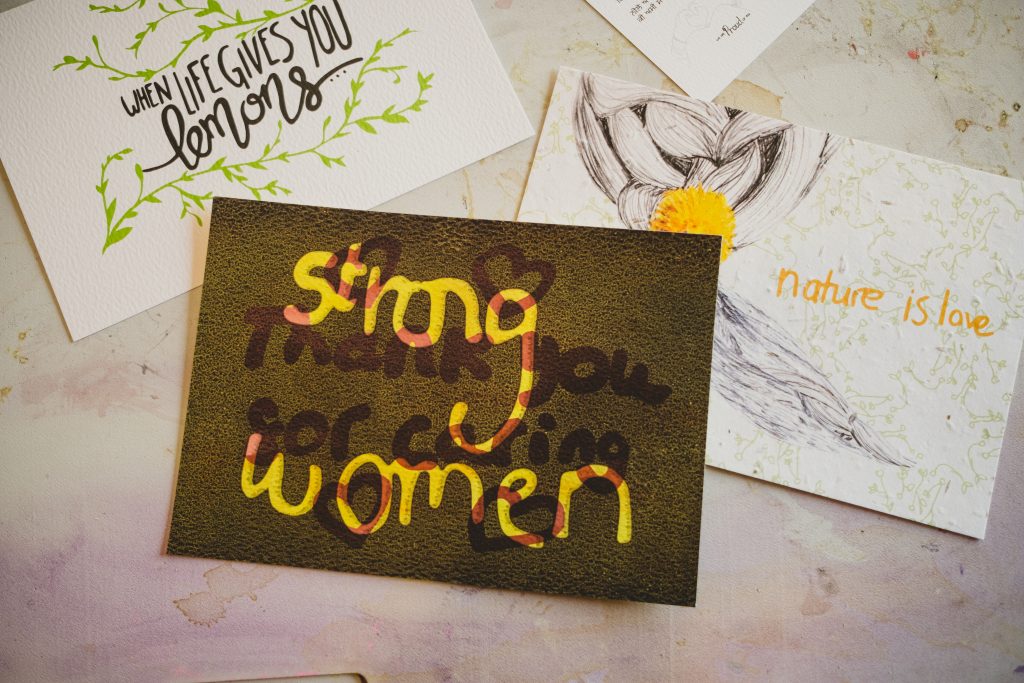 A card has the words 'strong women' visible on a transparent black backround. On the card can also be seen the message 'Thank you for caring'
