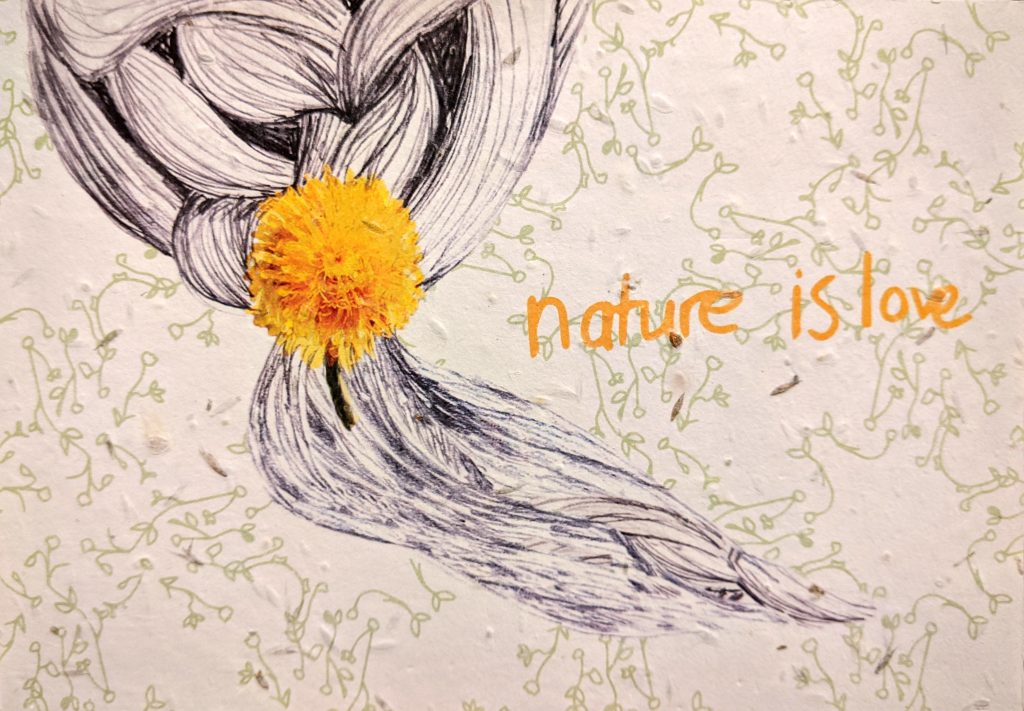 A background drawing of green leaves is speckled with flower seeds embedded in the paper. To the left is an illustration of plaited hair decorated with a yellow dandelion and the words 'nature is love' is printed in handwritten yellow text.