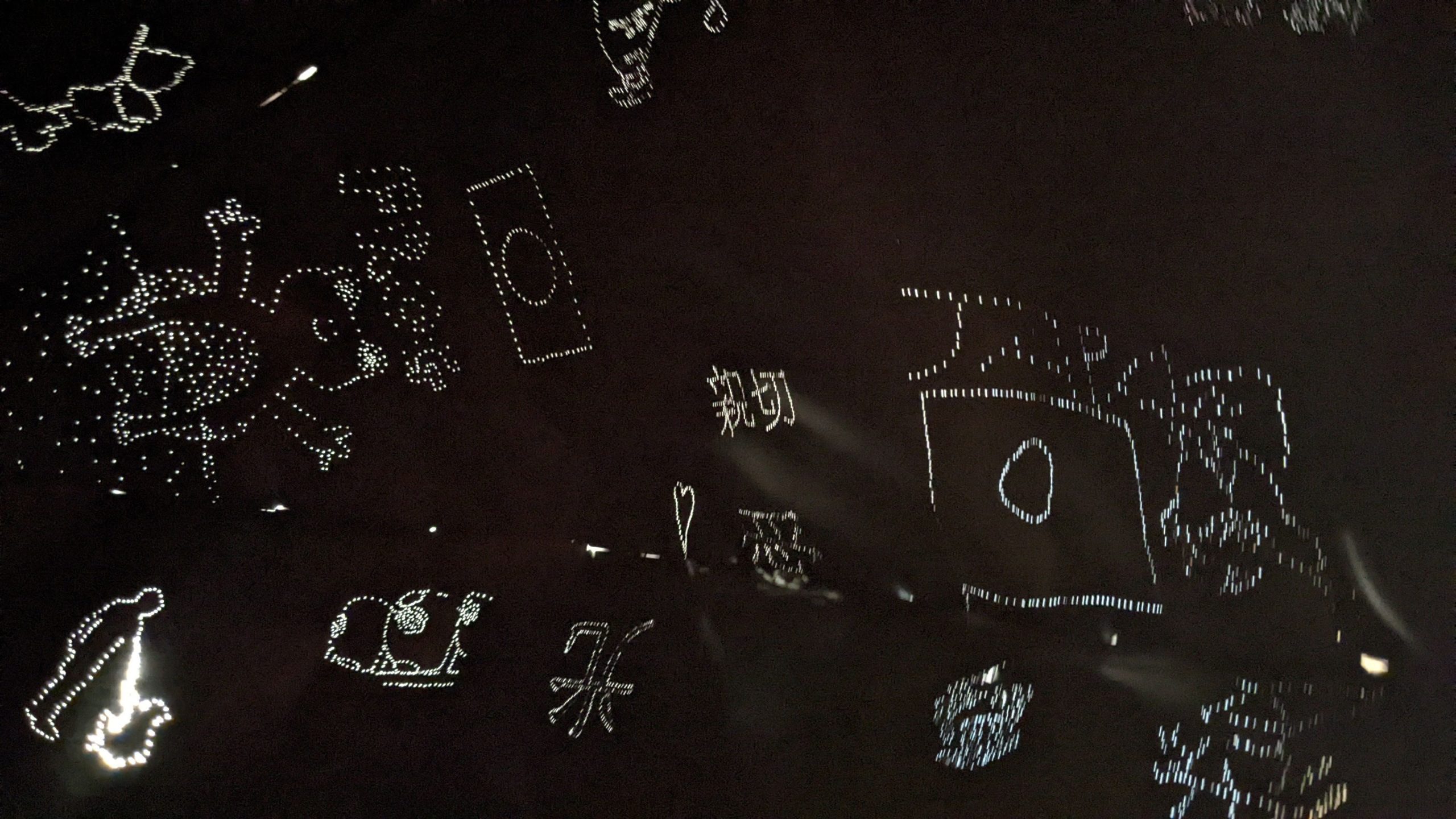 A black background has drawings made of dots of light. Drawings include a happy cartoon-like frog, the Japanese flag, a silhouette of a figure holding hands and the word Japan.