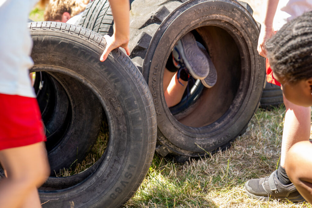 children are climbing through a tunnel of car tyres